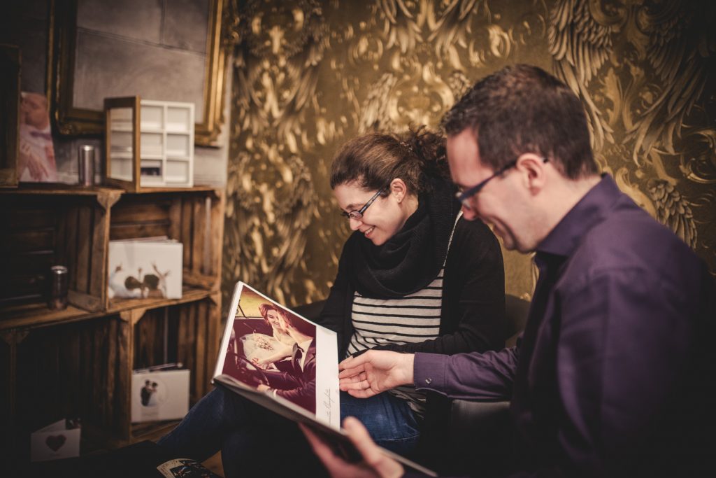 Paar blättert gemeinsam in einem Hochzeitsfotobuch