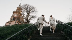 Brautpaar geht Hand in Hand eine Treppe zum Alten Hafenamt in Dortmund hinauf, im weichen Licht vor Sonnenuntergang.