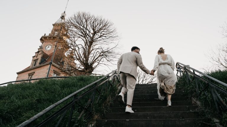 Brautpaar geht Hand in Hand eine Treppe zum Alten Hafenamt in Dortmund hinauf, im weichen Licht vor Sonnenuntergang.